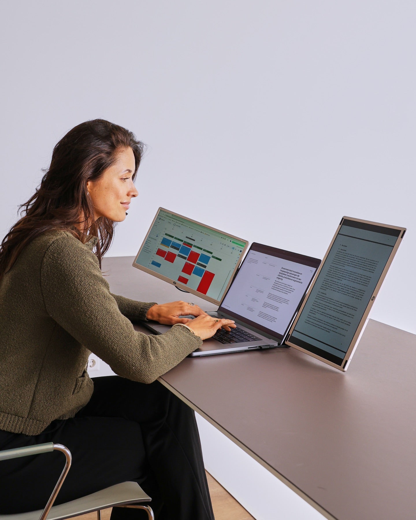 A professional works with a laptop and two additional monitors from Screenmate