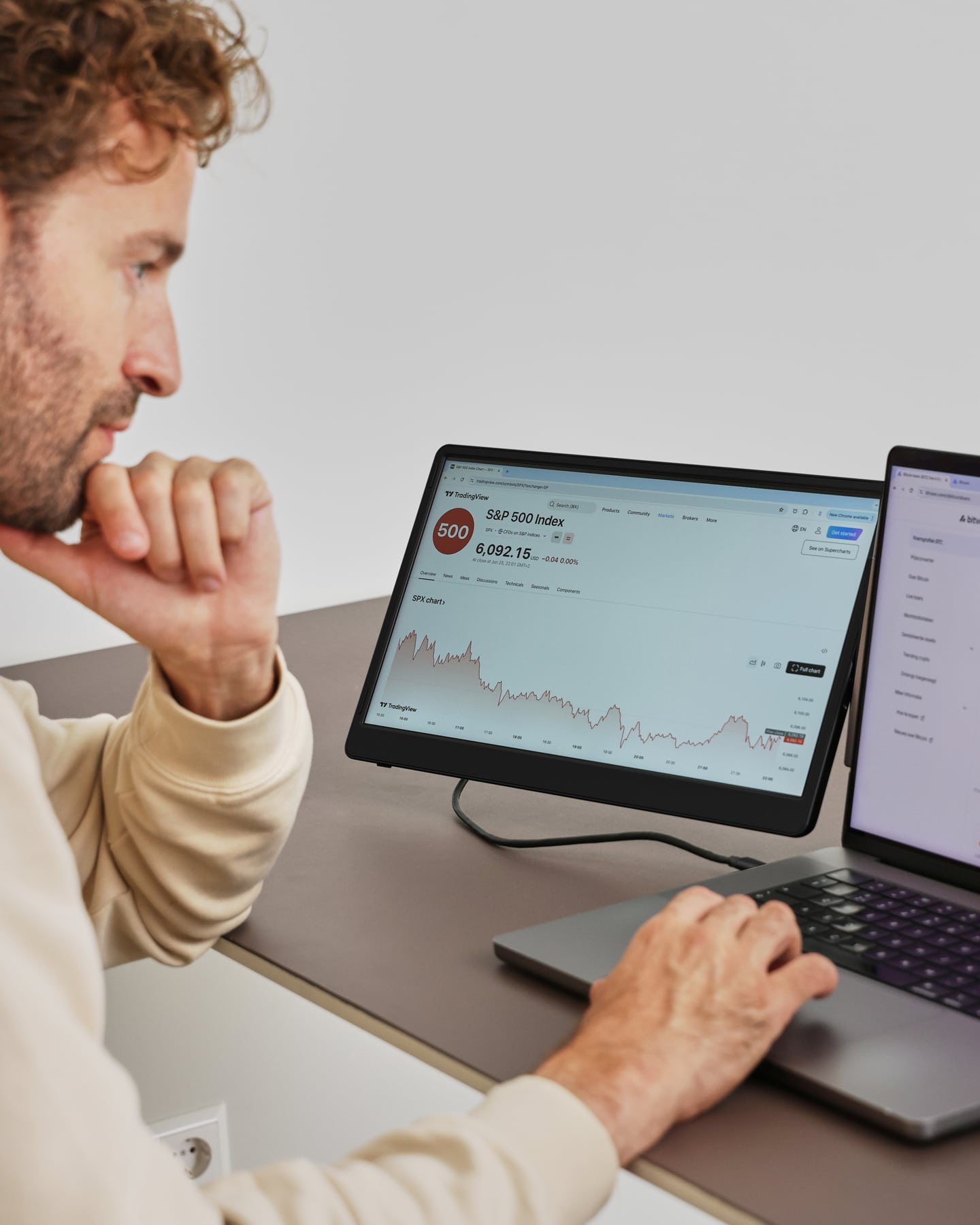 A man is working with the black Screenmate Flip next to his laptop