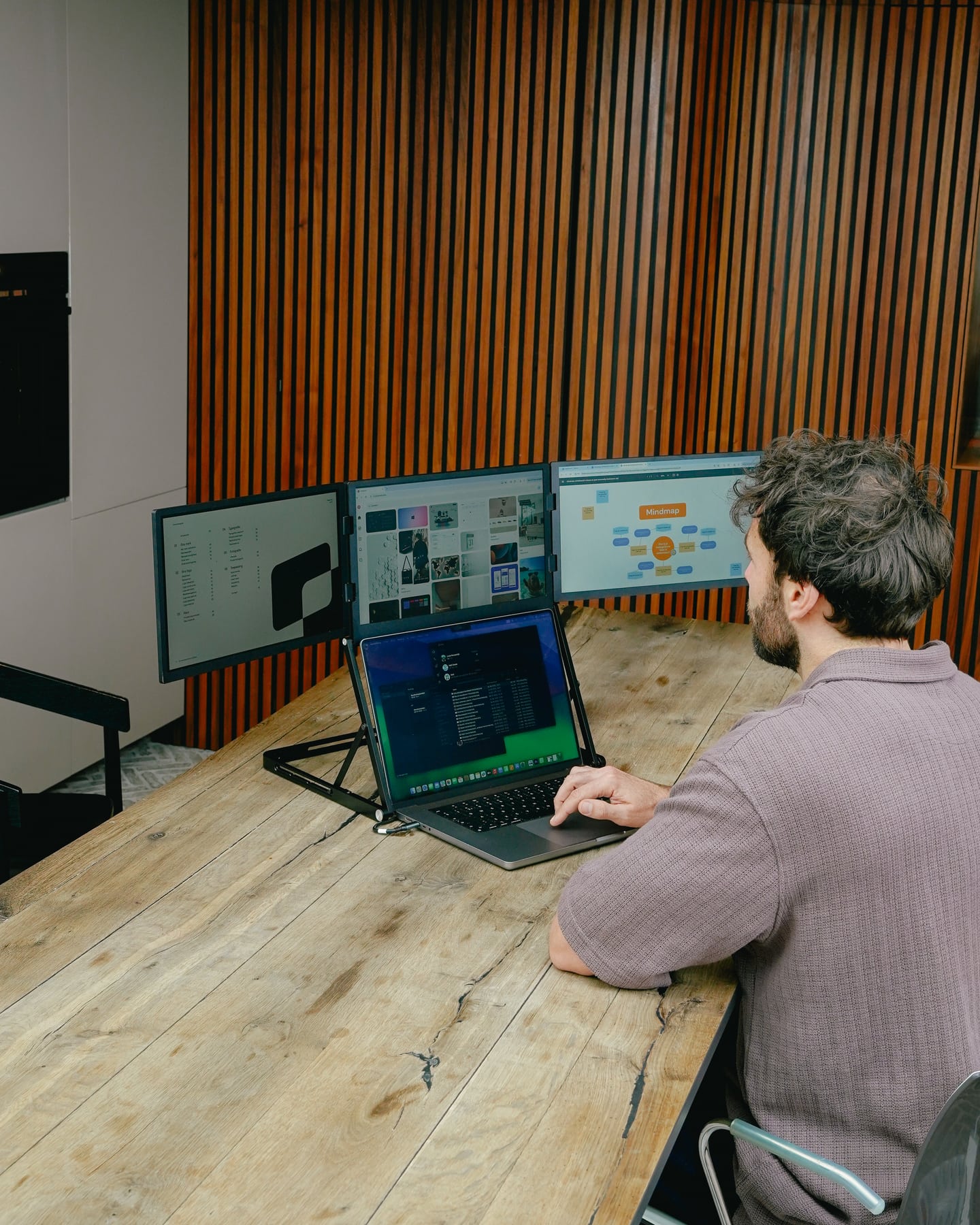 Ein Mann arbeitet mit dem Screenmate Panorama neben seinem Laptop