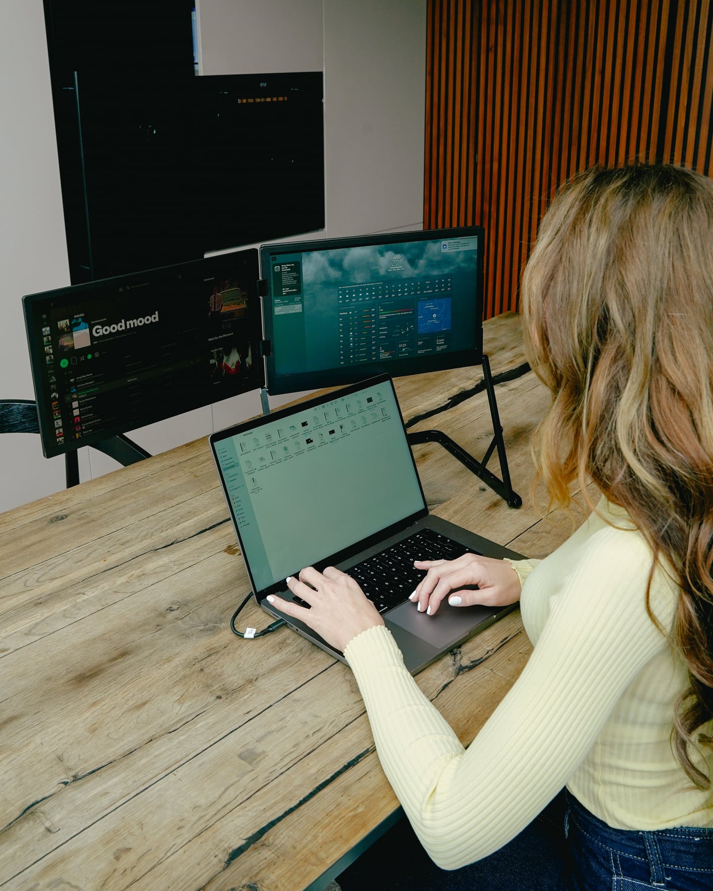 Frau arbeitet mit dem Screenmate Panorama an drei Bildschirmen