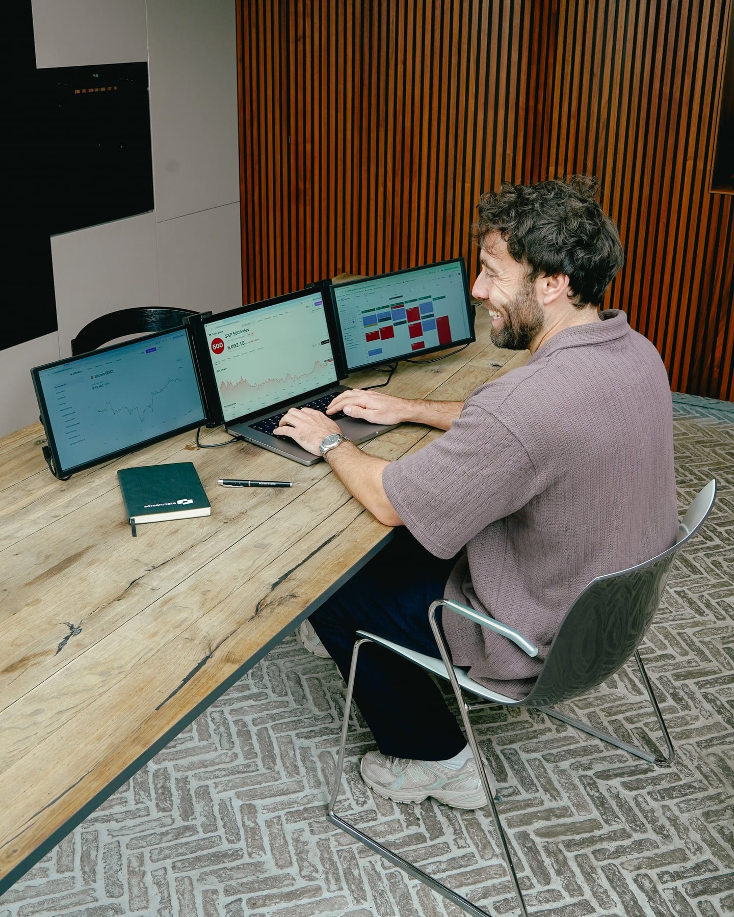 Man werkt met de zwarte Screenmate Expand en twee extra schermen