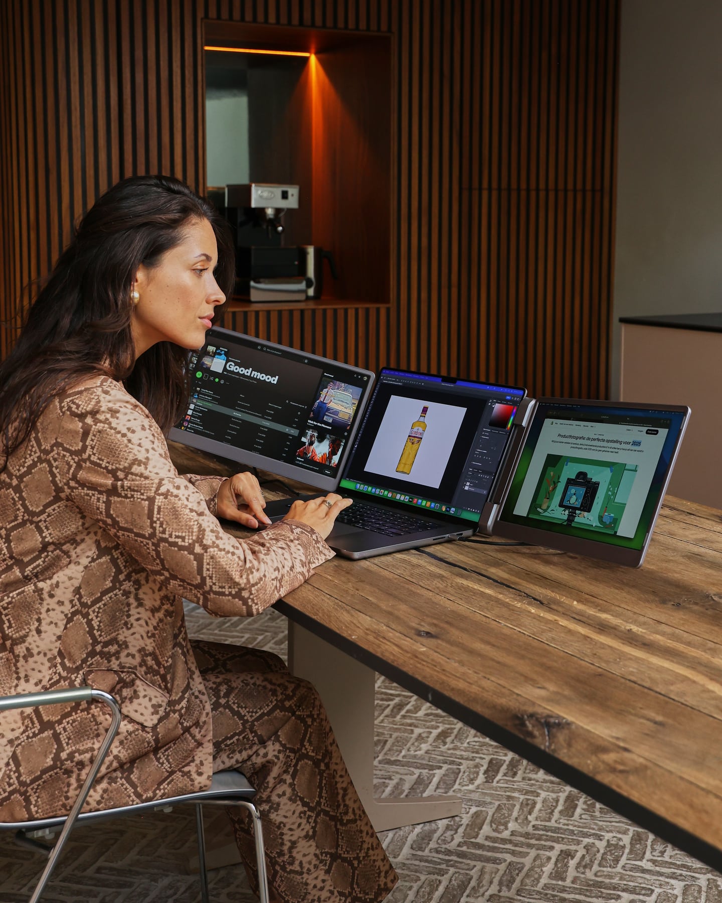 A woman is working on three screens using the gray Screenmate Flip